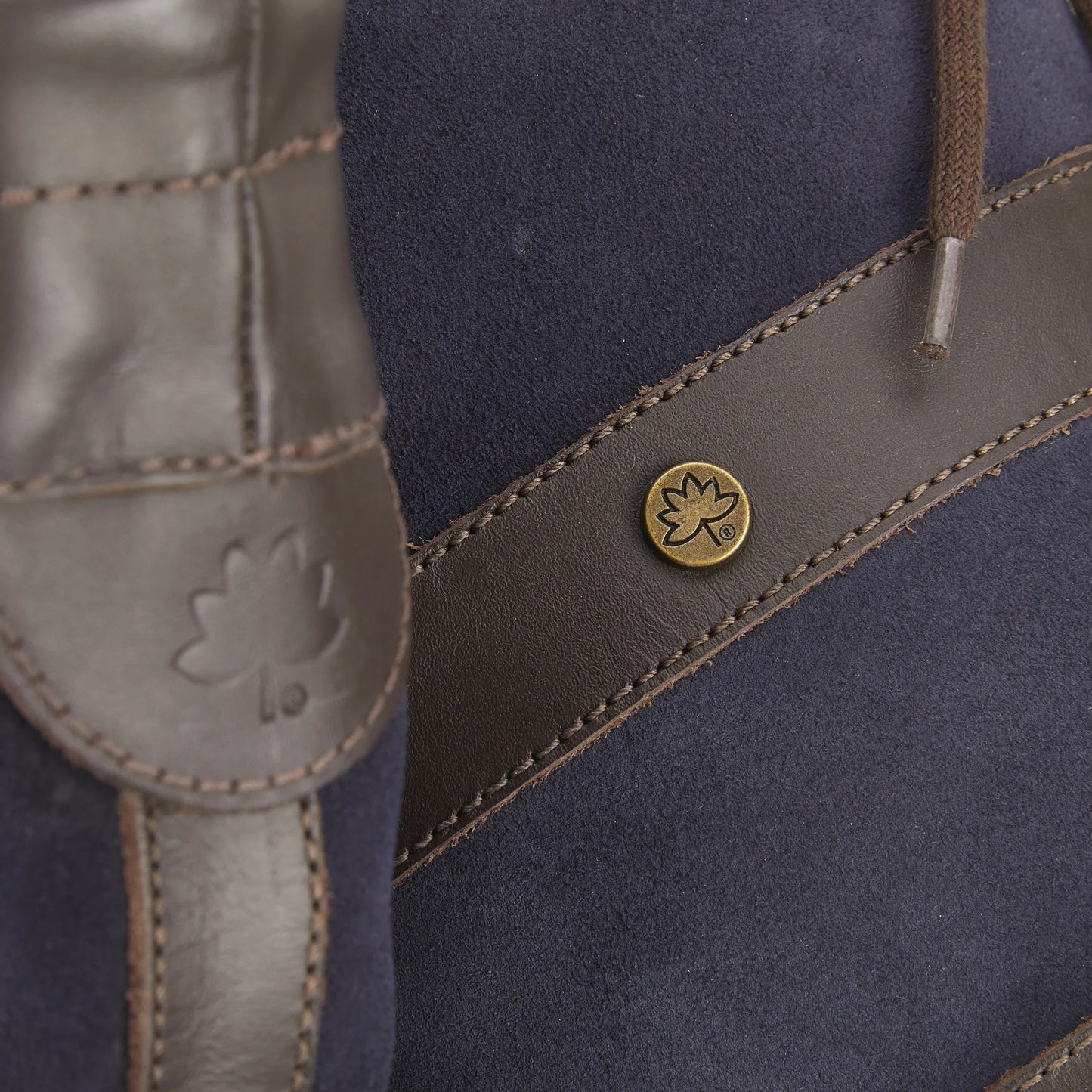 Close-up of handmade leather country boot with leaf emblem, durable stitching, and waterproof design